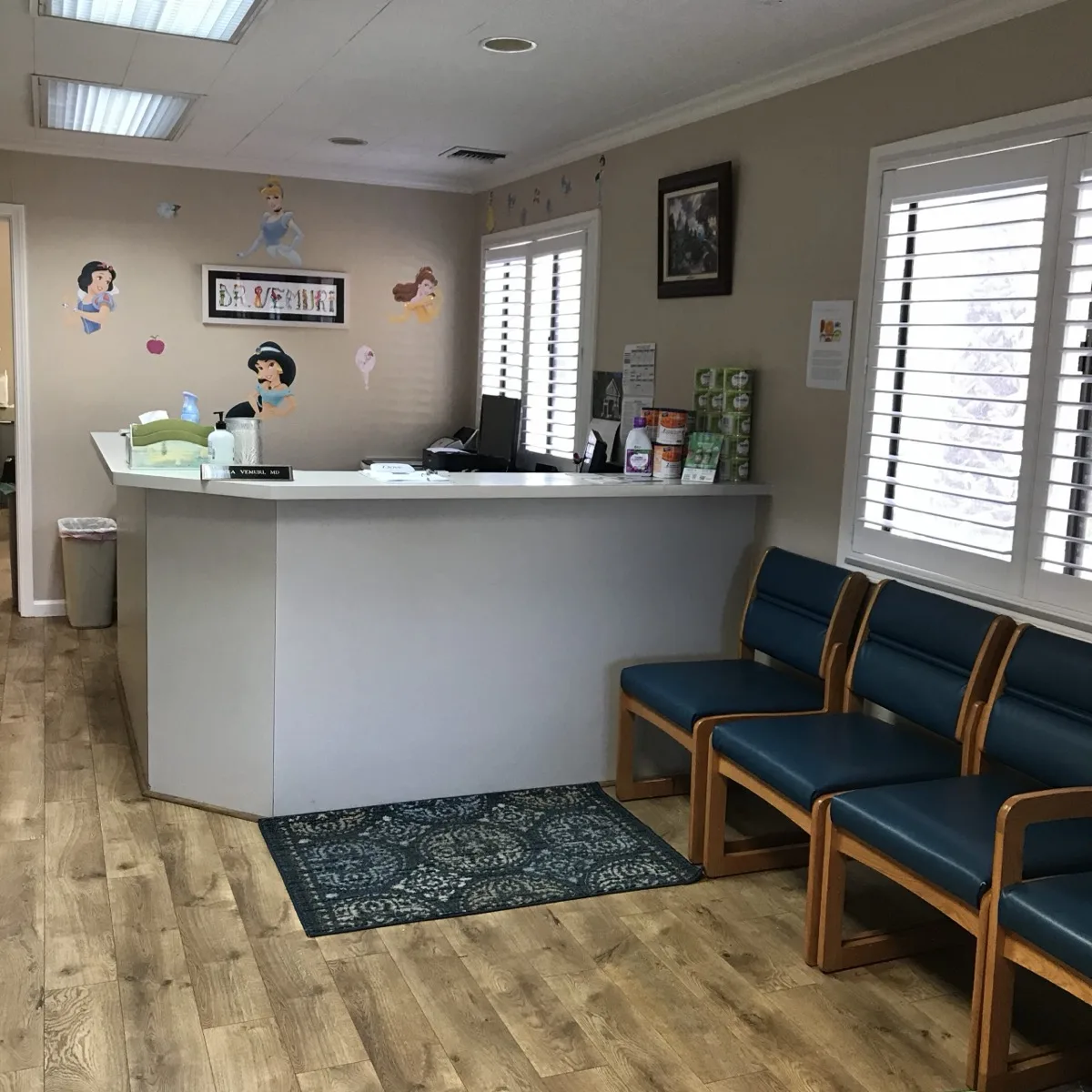 Front desk and waiting room with princess wall decals and blue chairs